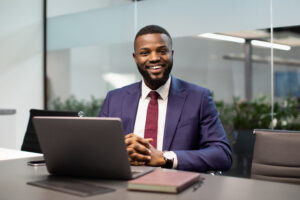 Cheerful Black Businessman Posing At Workdesk In Office - ADF PRO